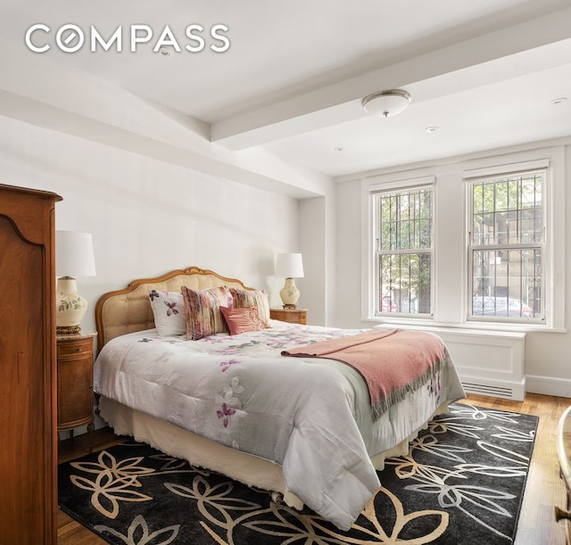 bedroom with hardwood / wood-style floors and beamed ceiling