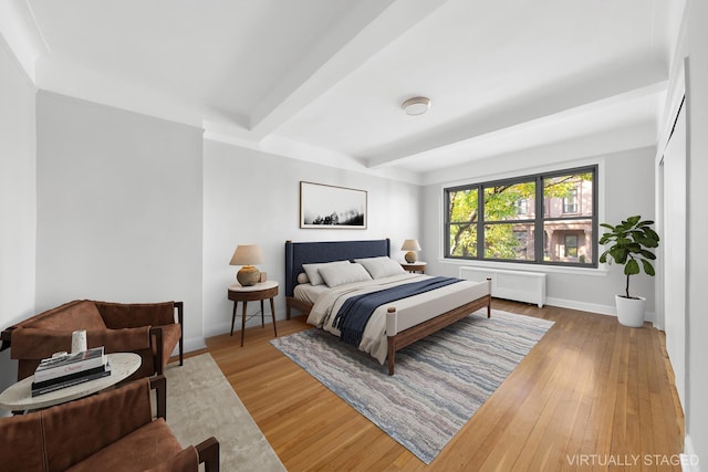 bedroom featuring beamed ceiling, wood-type flooring, and radiator heating unit