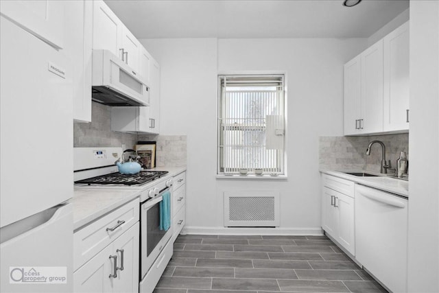 kitchen with light stone countertops, dark hardwood / wood-style flooring, white appliances, sink, and white cabinetry