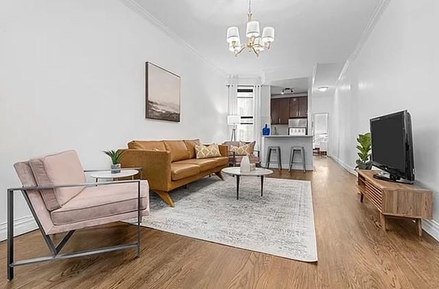 living room featuring hardwood / wood-style floors, a chandelier, and crown molding