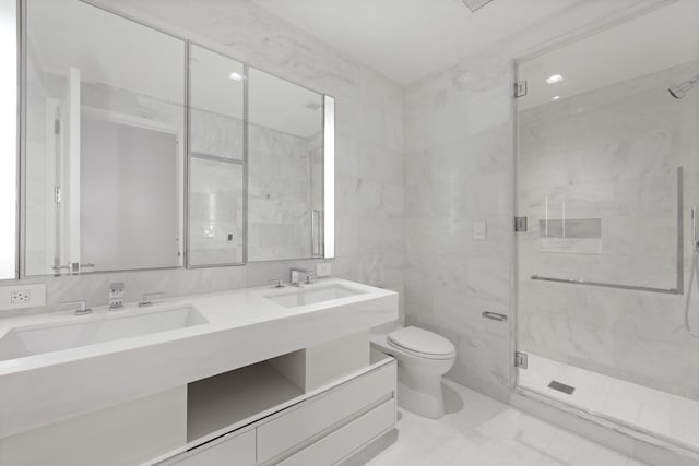 bathroom featuring toilet, vanity, tile walls, and a shower with door