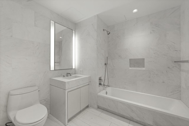 full bathroom with vanity, tiled shower / bath, toilet, and tile walls