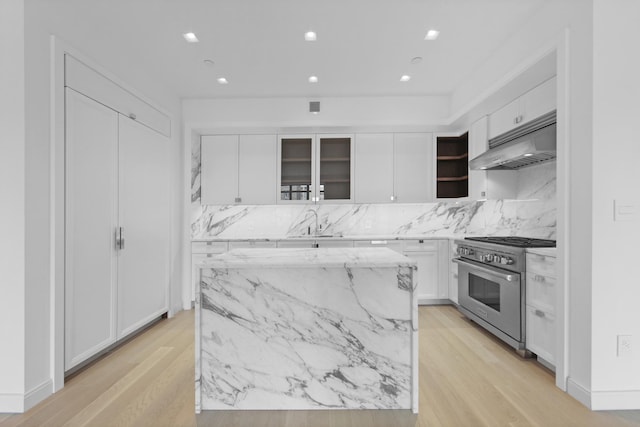 kitchen featuring high end stainless steel range, light stone countertops, a kitchen island, and white cabinets