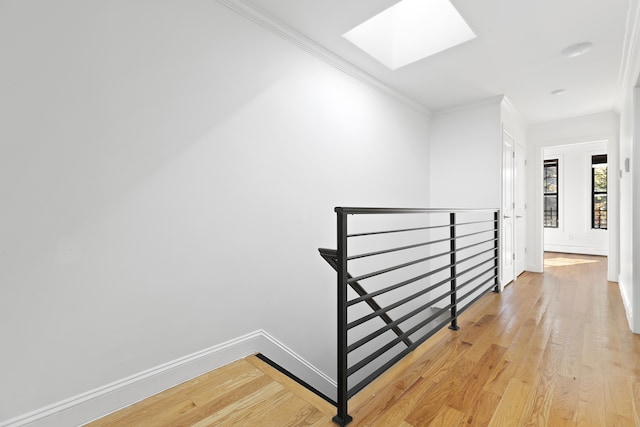 staircase featuring hardwood / wood-style floors, a skylight, and crown molding