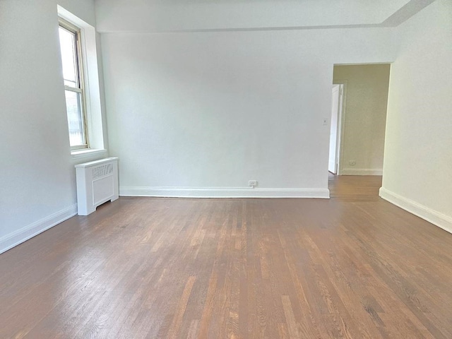 empty room with radiator and dark hardwood / wood-style floors