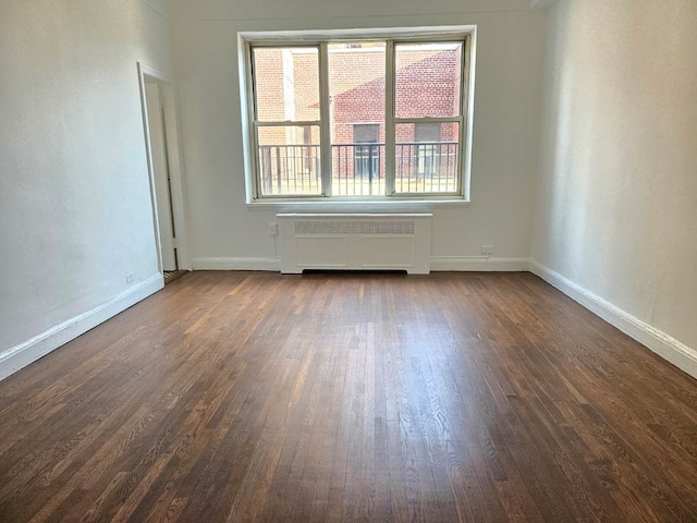 empty room with dark hardwood / wood-style floors and radiator heating unit