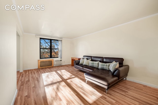 living room with ornamental molding, a wall mounted air conditioner, and light wood-type flooring