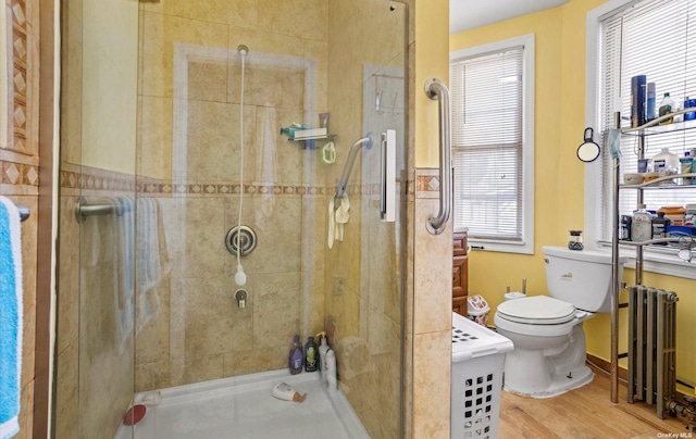 bathroom with hardwood / wood-style flooring, toilet, a shower with door, and radiator