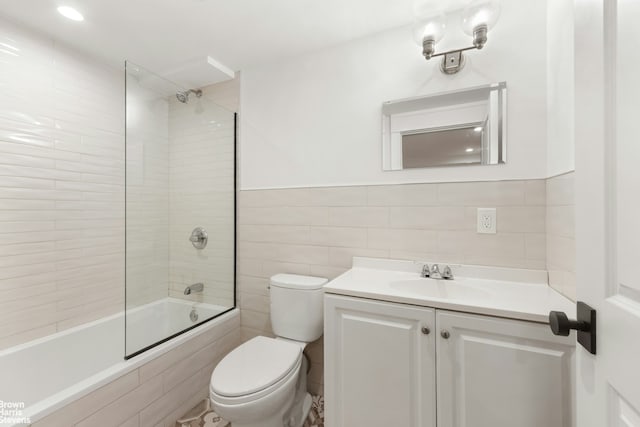 full bathroom featuring tile walls, vanity, tiled shower / bath combo, and toilet