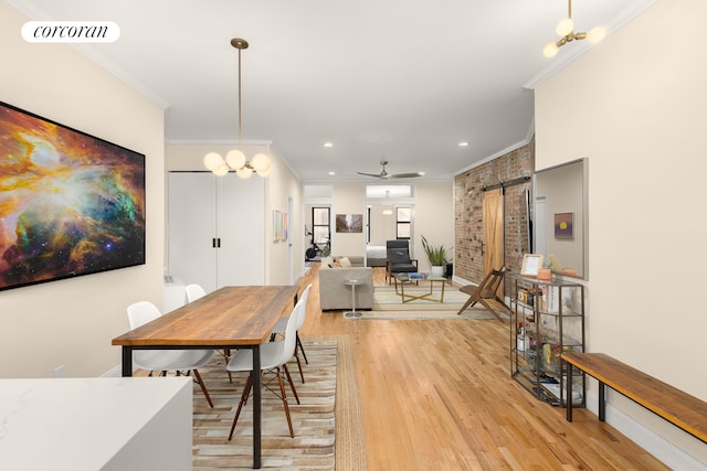 dining space featuring a barn door, crown molding, light hardwood / wood-style floors, and ceiling fan with notable chandelier