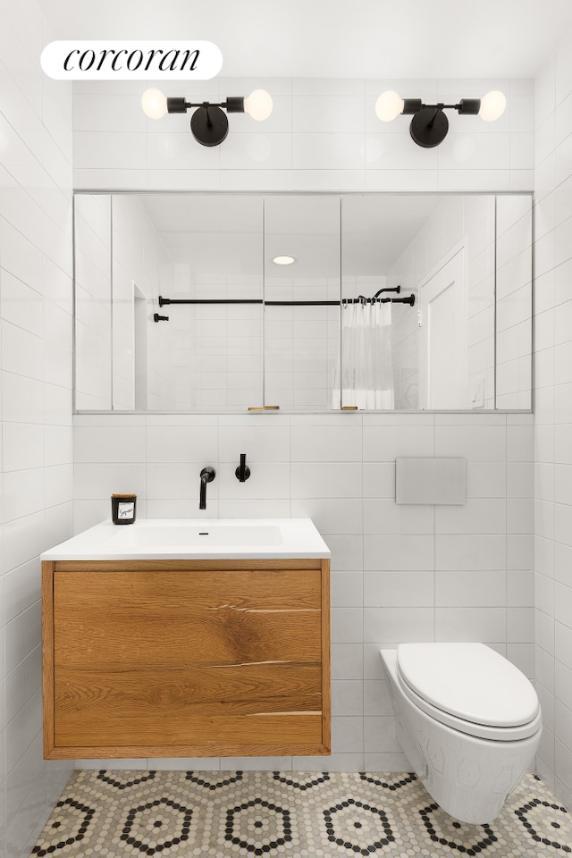 bathroom featuring tile patterned floors, vanity, toilet, and tile walls