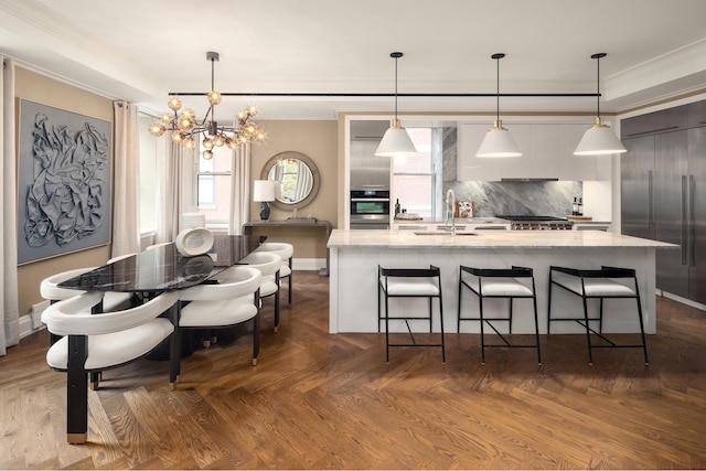 kitchen with parquet floors, backsplash, a chandelier, pendant lighting, and a spacious island