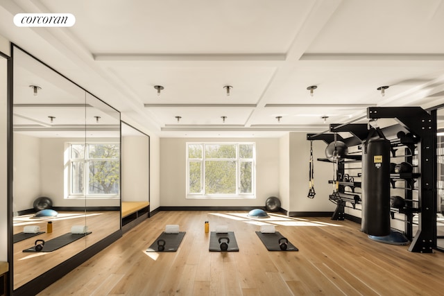 workout area with coffered ceiling and light wood-type flooring