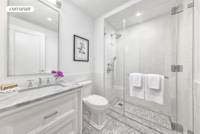 bathroom with vanity, toilet, walk in shower, and tile walls