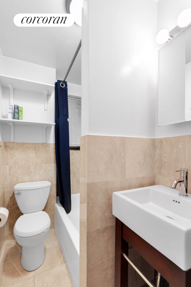 full bathroom featuring shower / bath combo, tile patterned flooring, toilet, vanity, and tile walls