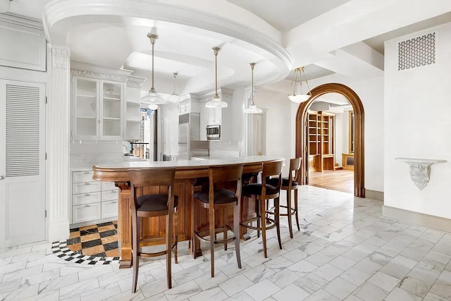 bar with built in appliances, white cabinetry, and hanging light fixtures