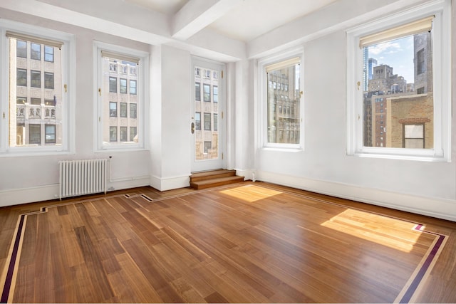 unfurnished sunroom with beamed ceiling and radiator