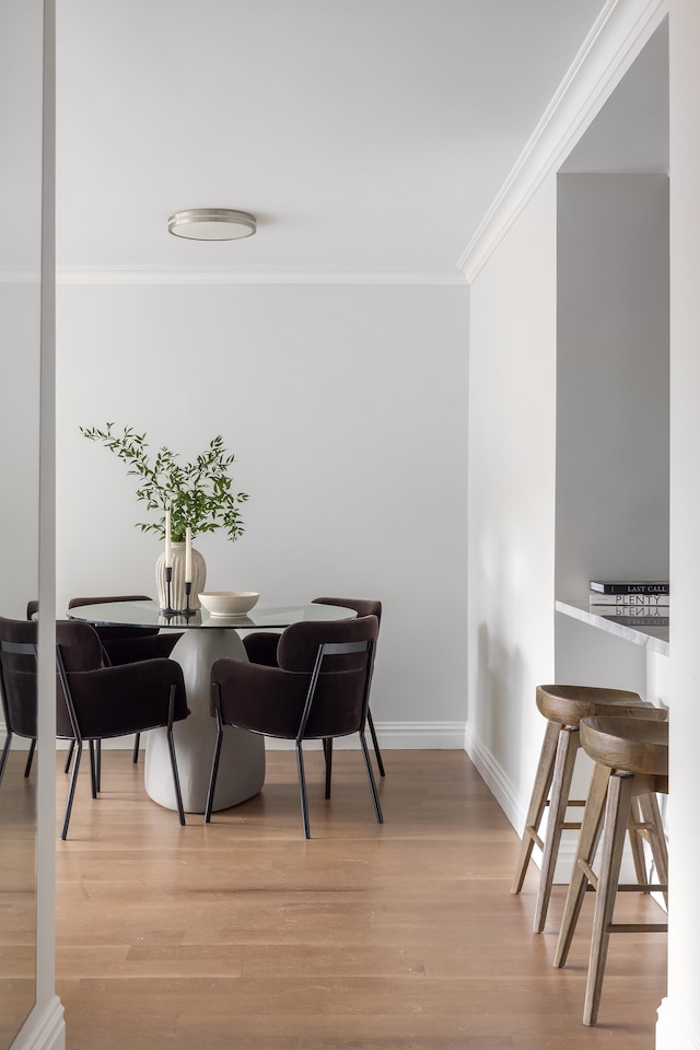 dining area with light wood-type flooring and ornamental molding