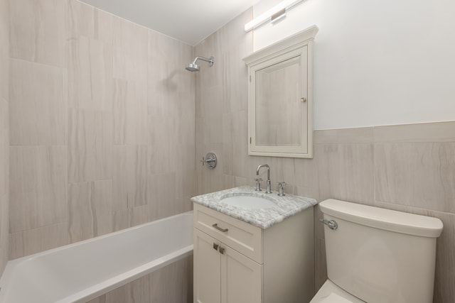 full bathroom featuring tiled shower / bath combo, toilet, tile walls, and vanity