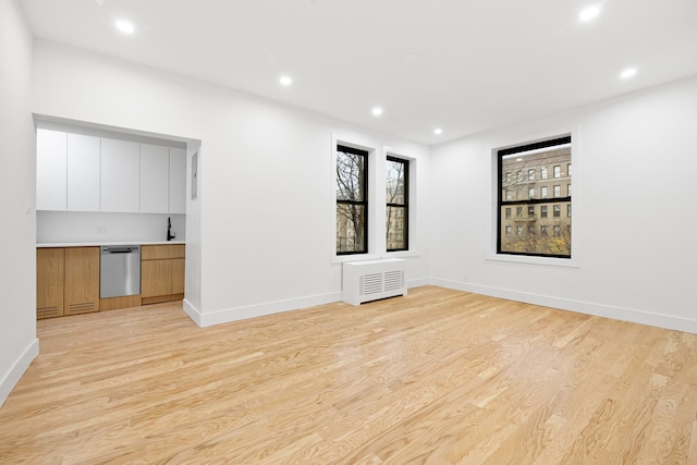 unfurnished living room featuring radiator heating unit and light hardwood / wood-style floors