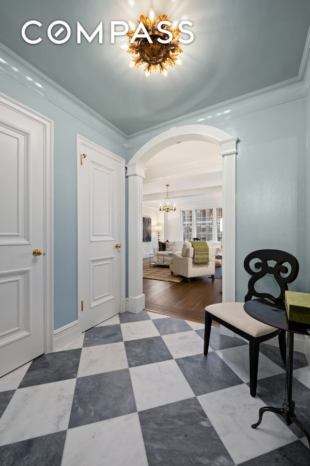 foyer entrance with a chandelier, ornate columns, and crown molding