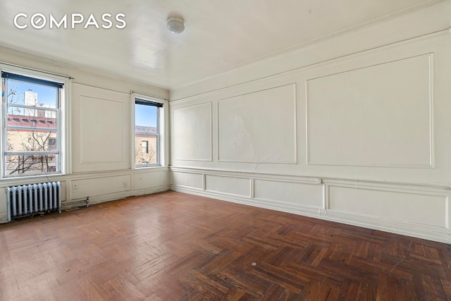 spare room featuring radiator and parquet flooring