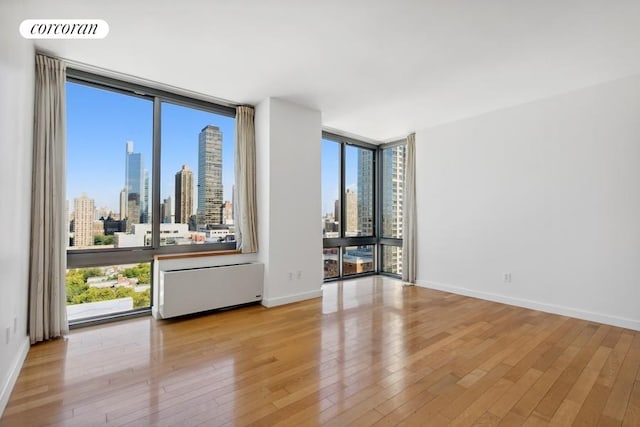 unfurnished room with expansive windows and light hardwood / wood-style flooring