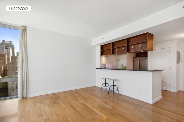 kitchen featuring a kitchen breakfast bar, high end fridge, light wood-type flooring, and kitchen peninsula