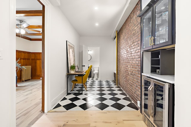 corridor with wine cooler, radiator, and brick wall