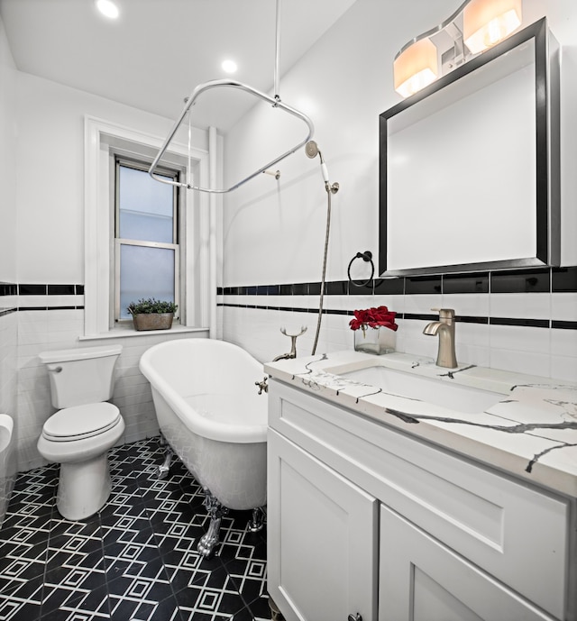 bathroom featuring a washtub, toilet, tile walls, and vanity