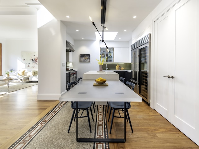 dining space with light hardwood / wood-style floors and a skylight