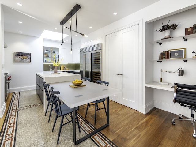 kitchen featuring dark hardwood / wood-style flooring, built in desk, decorative light fixtures, white cabinets, and built in refrigerator