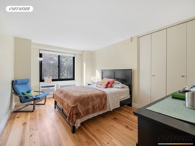 bedroom with a wall mounted air conditioner and light wood-type flooring