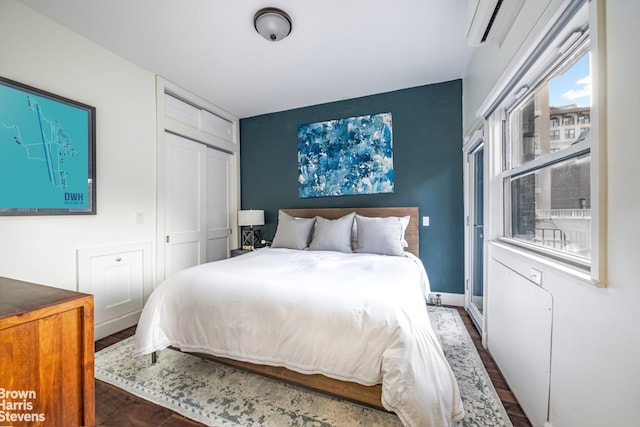 bedroom with a wall unit AC, a closet, and dark wood-type flooring