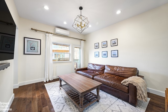 living room with an AC wall unit, an inviting chandelier, and hardwood / wood-style flooring