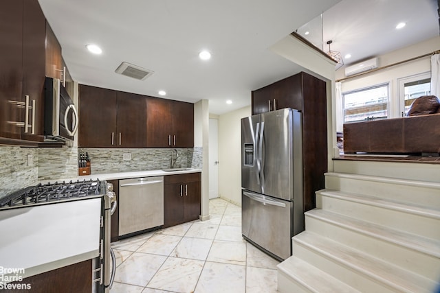 kitchen featuring backsplash, sink, appliances with stainless steel finishes, a wall mounted AC, and dark brown cabinets