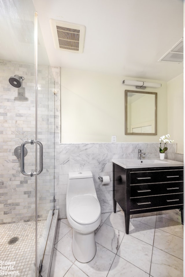 bathroom featuring vanity, toilet, a shower with shower door, and tile walls