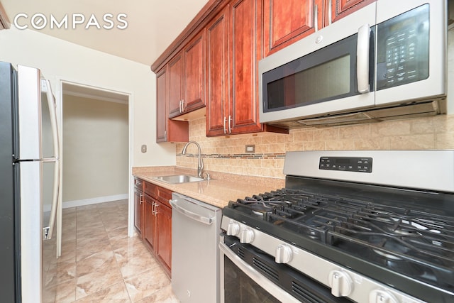 kitchen with backsplash, light stone countertops, sink, and appliances with stainless steel finishes