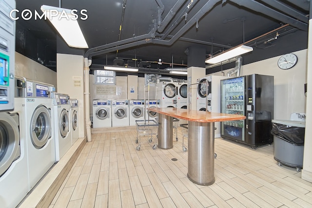 clothes washing area with washer and clothes dryer, stacked washer / dryer, and light hardwood / wood-style flooring