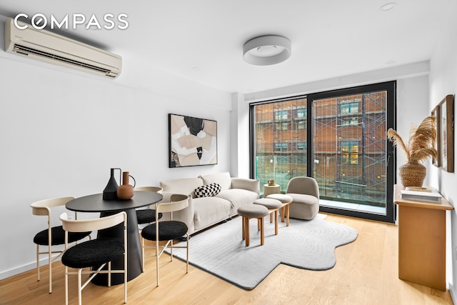 living room with an AC wall unit and light hardwood / wood-style flooring