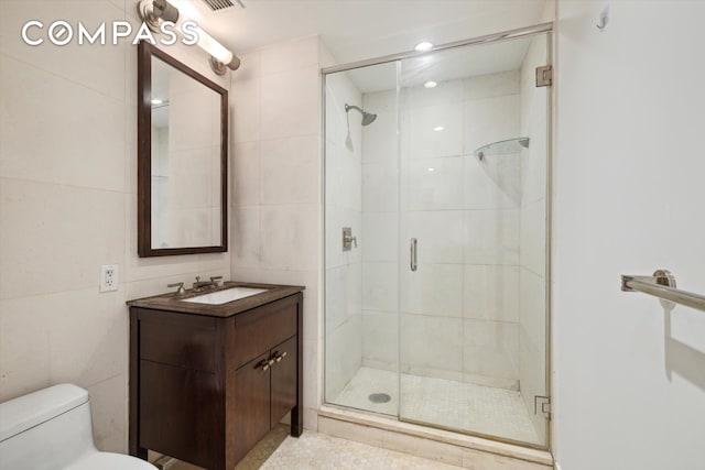 bathroom featuring toilet, vanity, tile walls, and walk in shower