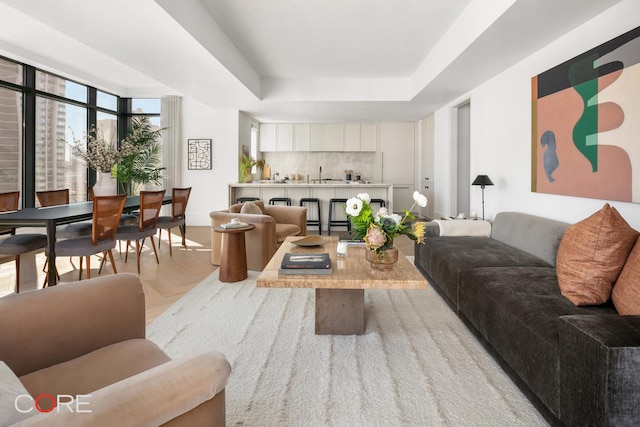 living room featuring a raised ceiling, a wall of windows, and light parquet flooring