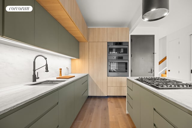 kitchen featuring light stone countertops, stainless steel appliances, light hardwood / wood-style floors, and sink