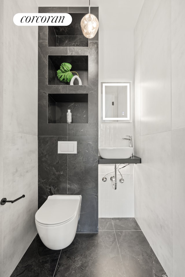 bathroom with sink, toilet, and tile walls