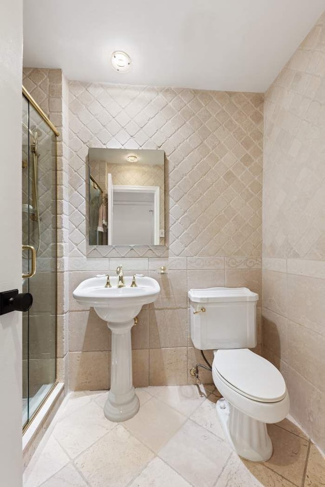 bathroom featuring toilet, a shower with shower door, and tile walls