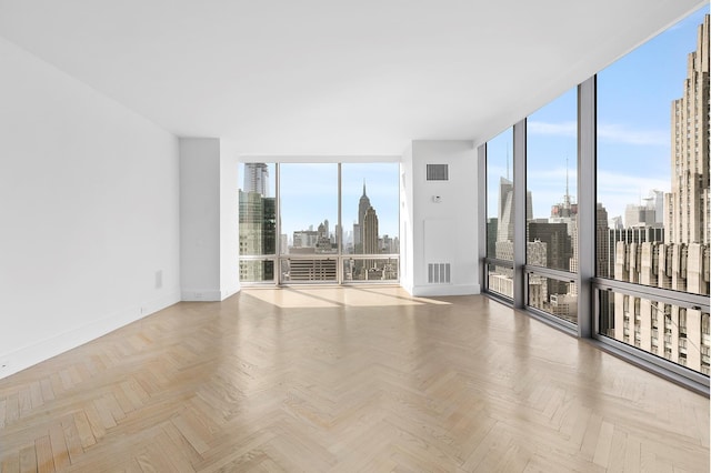 empty room with a wealth of natural light, light parquet floors, and a wall of windows