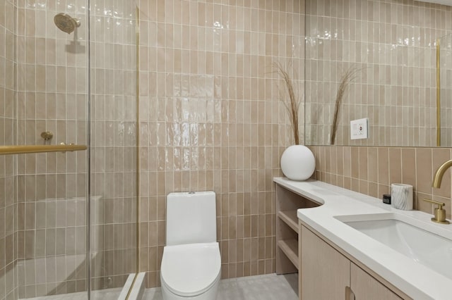 bathroom with vanity, a shower with door, toilet, and tile walls