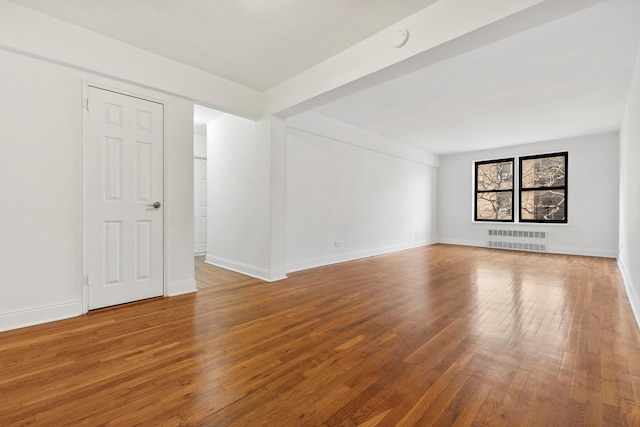 unfurnished living room with radiator and hardwood / wood-style flooring