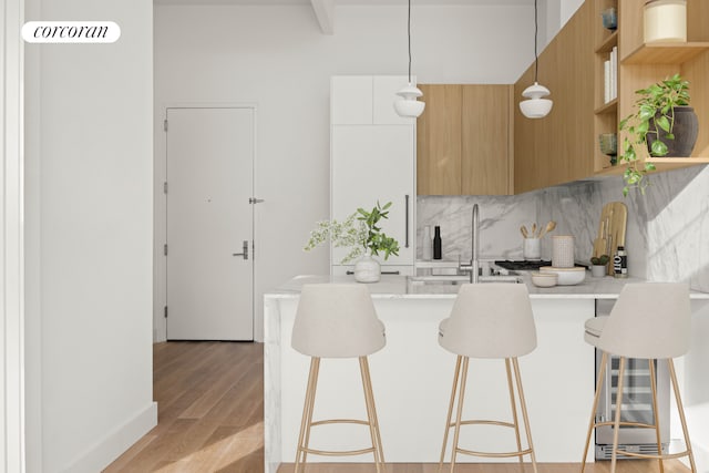 kitchen with kitchen peninsula, a kitchen breakfast bar, backsplash, decorative light fixtures, and white cabinets