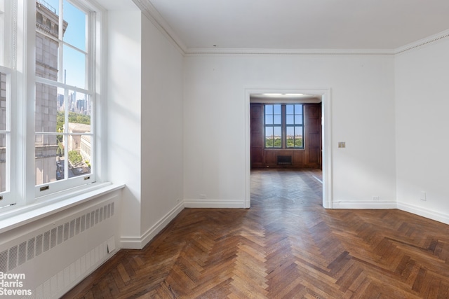 empty room featuring radiator heating unit, dark parquet floors, and plenty of natural light